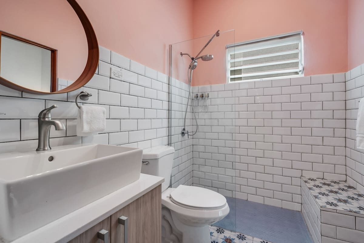 Une salle de bain avec un lavabo, des toilettes et une douche, le tout de couleur blanche.
