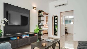 A modern living room with a flat-screen TV, a sofa, a coffee table, and a bookshelf.