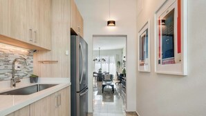 A modern kitchen with a stainless steel refrigerator, wooden cabinets, and a granite countertop.