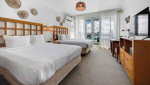 Habitació d'hotel amb dos llits, un panell de fusta al capçal, un mirall gran, un taulell i un balcó amb vistes.