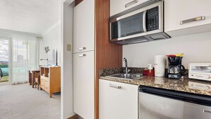 Cuina moderna amb microones, rentapelats i cafetera. Es veu un balcó amb una cadira i una taula.