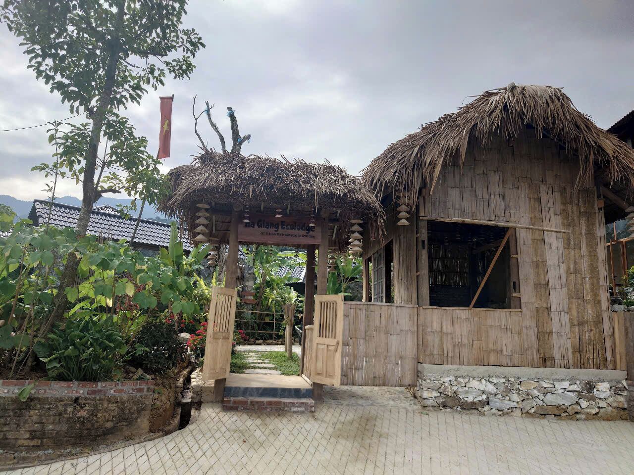 Una estructura tradicional de bambú con techo de paja, un portón de madera y un cartel que indica que forma parte del Centro Ecológico de Giang.