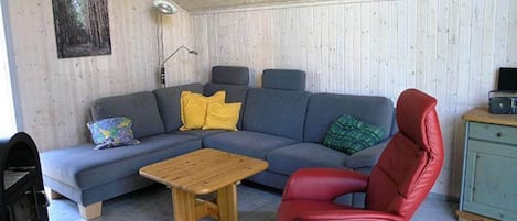 A living room with a sectional sofa, a red chair, a wooden coffee table, and a small cabinet.
