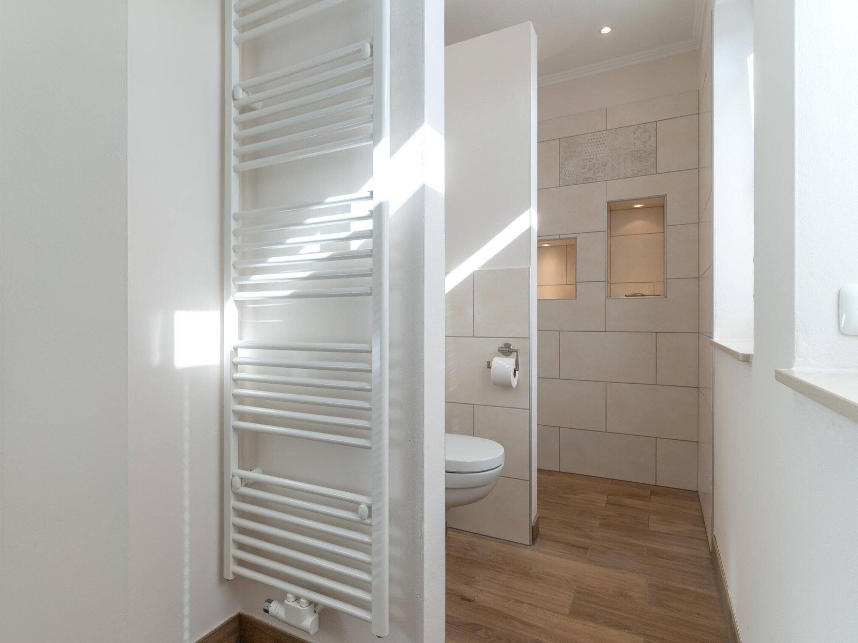 A modern bathroom with a white toilet, a towel rack, and a shower area.