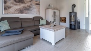 Una sala de estar con sofá, una mesa de centro, un aparador, chimenea y un cuadro en la pared.