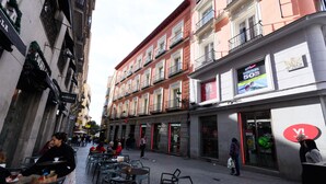 A street with outdoor seating, shops, and a building with a large sign.