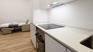 Ett modernt kök med en inbyggd ugn, en bänkskiva och en liten sittplats med en stol och en kudde.