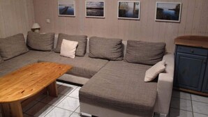 A cozy living room with a sectional sofa, a wooden coffee table, and a cabinet. - Ferienhaus im Ferienpark Mirow (Mirow)