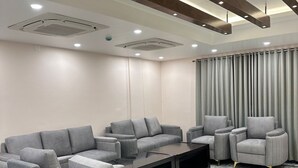 A modern living room with a grey sectional sofa, armchairs, and a coffee table. - LUXE HAVEN RESIDENCY (Budgam)