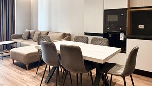 A modern living room with a sofa, a dining table with chairs, and a kitchen area with appliances. - Blue Boutique Apartments 1 (Farke)
