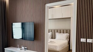 A modern bedroom with a built-in TV, a bedside table, and a bed with a headboard. - Blue Boutique Apartments 1 (Farke)