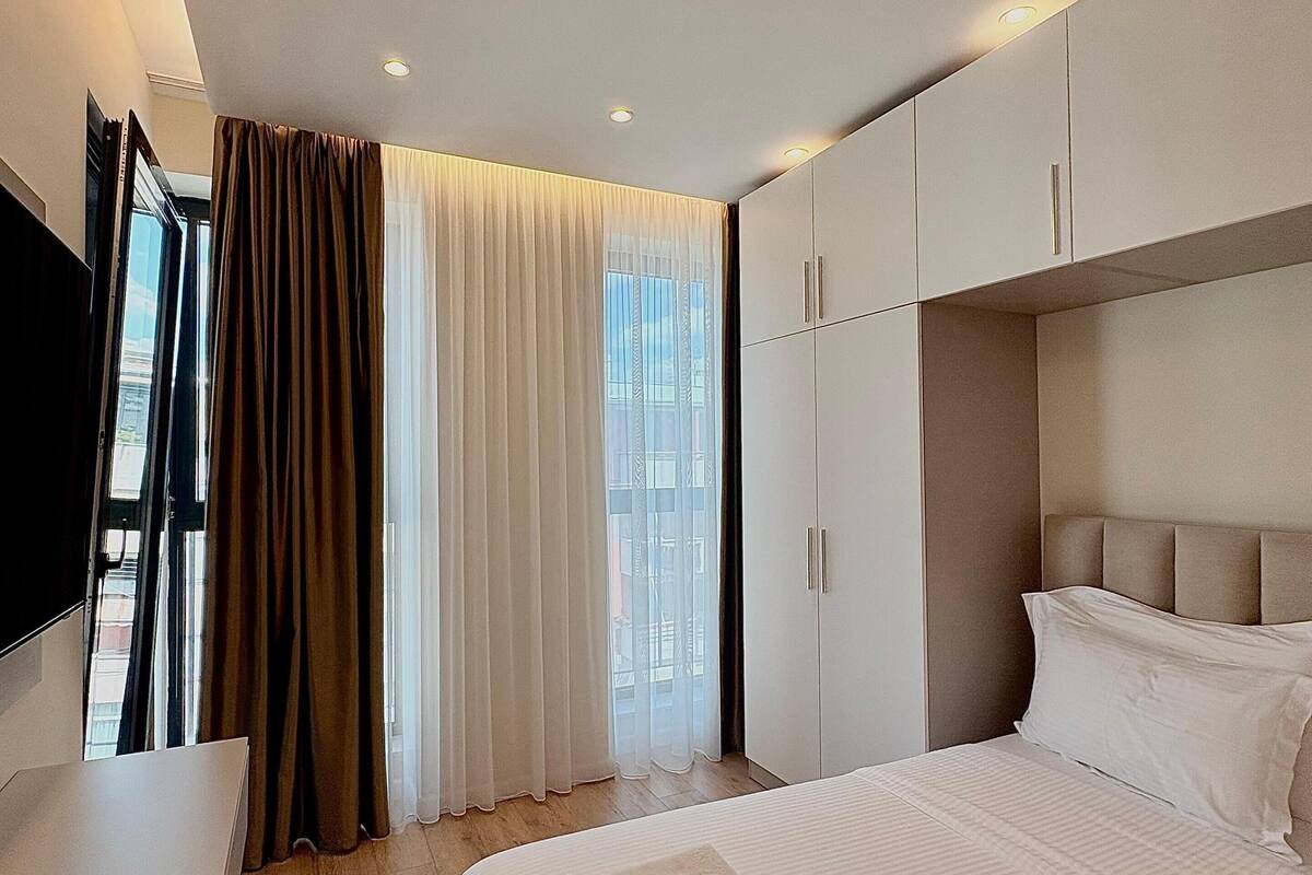 Quarto de hotel com cama, escrivaninha e guarda-roupa.