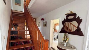 A wooden staircase with a patterned carpet leading to a room with a round table and a mirror.