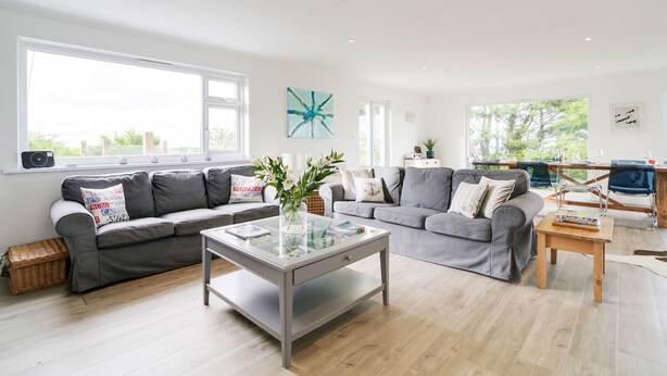 A modern living room with a grey sofa set, a glass coffee table, and a wooden side table.
