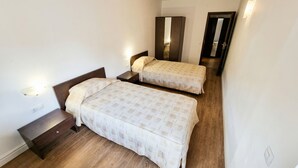 A bedroom with two single beds, a wooden floor, a nightstand, a mirror, and a wall-mounted light. - Mountain Paradise 2 - Cosy 2 Bed Mountain View Apartment - Washer (Bansko)