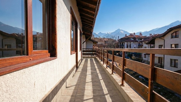 A balcony with a view of snow-capped mountains, wooden railings, and a tiled floor. - Mountain Paradise 2 - Cosy 2 Bed Mountain View Apartment - Washer (Bansko)
