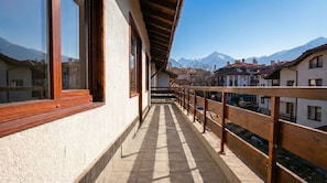 A balcony with a view of snow-capped mountains, wooden railings, and a tiled floor. - Mountain Paradise 2 - Cosy 2 Bed Mountain View Apartment - Washer (Bansko)