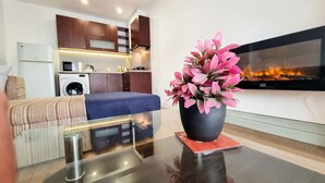 A modern living room with a sofa, a glass coffee table, a potted plant, and a flat-screen TV mounted on the wall. - Mountain Paradise 2 - Cosy 2 Bed Mountain View Apartment - Washer (Bansko)