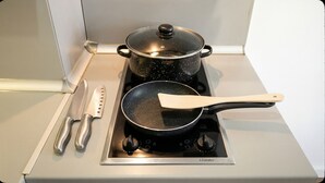 A kitchen with a stove, a frying pan, a spatula, and a knife. - Mountain Paradise 2 - Cosy 2 Bed Mountain View Apartment - Washer (Bansko)
