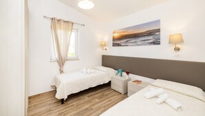 A bedroom with two beds, a window with curtains, a painting of a sunset, and two bedside lamps. - Farmhouse in Vieste Near Gargano Coast (Vieste)