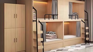 A bunk bed room with a wooden wardrobe and a checkered floor.