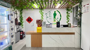 A reception area with a wooden counter, a digital display, and a wall-mounted sign.