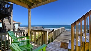 Una terraza de madera con vista al océano, una silla verde y una barandilla de madera.