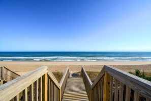 A wooden boardwalk leading to a beach with a clear blue sky. - Appreciate the oceanfront at Oakley's Oasis, Surf City, NC - perfect for 10! (Surf City)