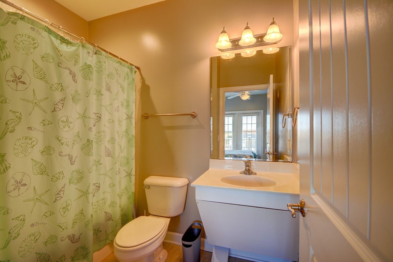 A bathroom with a toilet, sink, and mirror.