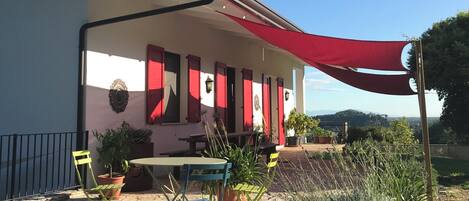 A building with a red awning, outdoor seating, and potted plants.