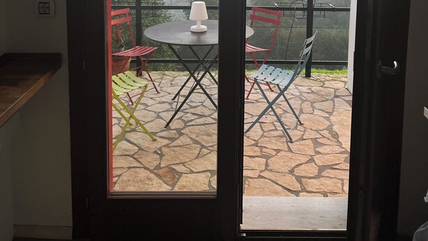 Habitación con puerta de vidrio corredera que da a un patio exterior con mesa y sillas.