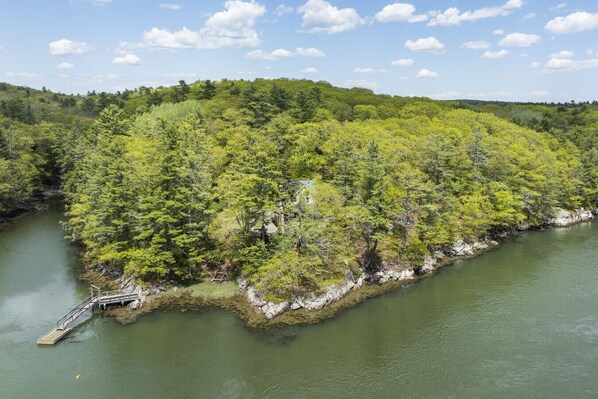A forested island with a dock and a small bridge.