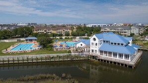 A waterfront property with a large swimming pool, a dock, and a building with a blue roof.