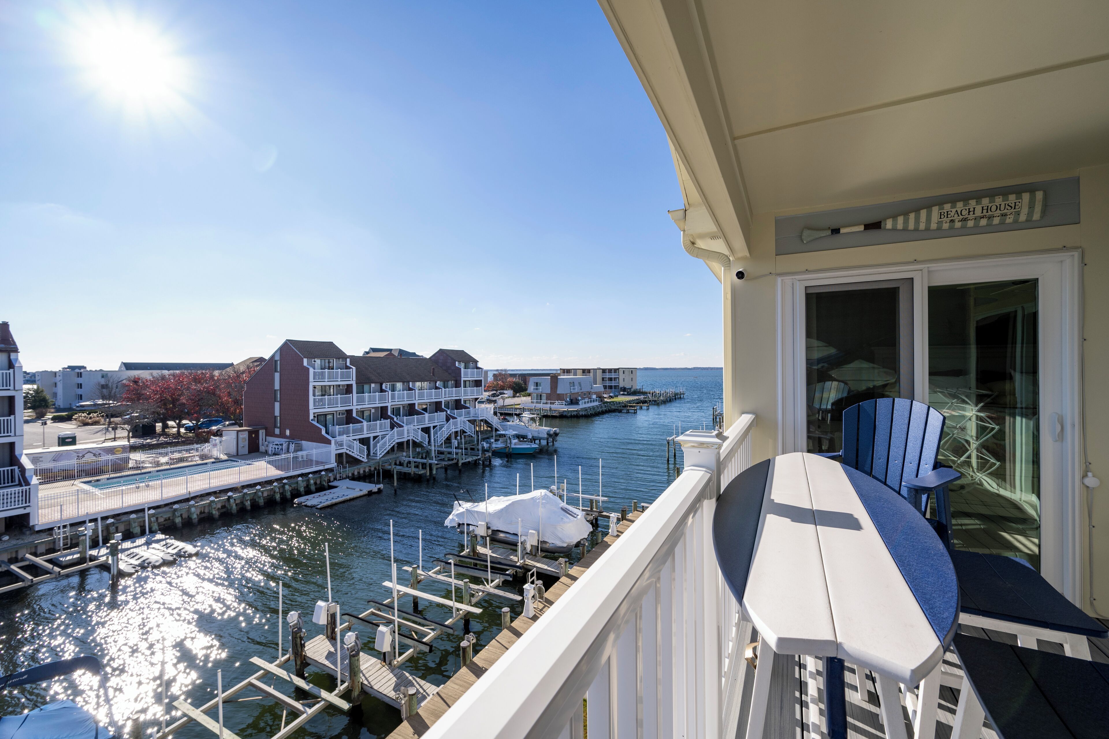 Een balkon met uitzicht op een jachthaven, liggende boten en gebouwen op de achtergrond.