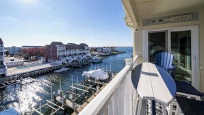 A balcony with a view of a marina, docked boats, and buildings in the background.