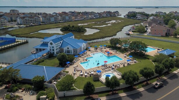A resort with a large swimming pool, a dock, and a view of the water.