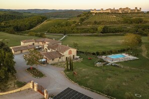 A villa with a swimming pool, surrounded by a well-maintained garden and a view of a historic castle.