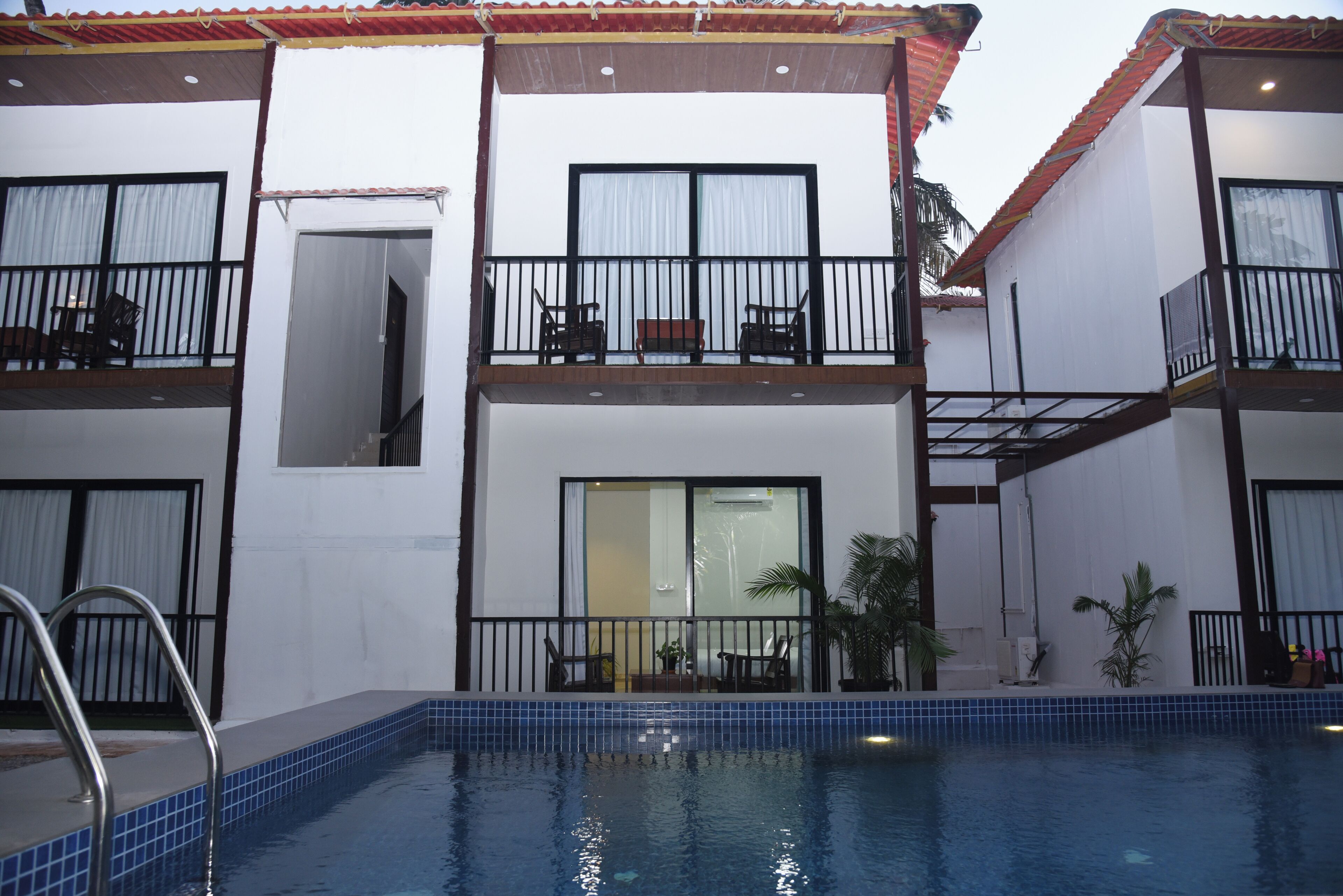 Un hôtel doté d’une piscine, de balcons aménagés avec du mobilier et d’un sol carrelé.