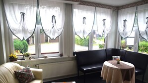 A room with a sofa, a table, and a window with curtains.