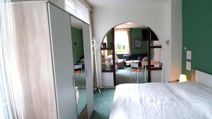A bedroom with a bed, a mirror, a desk, and a chair.