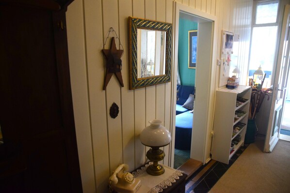 A hallway with a telephone, a lamp, a mirror, and a star decoration on the wall.