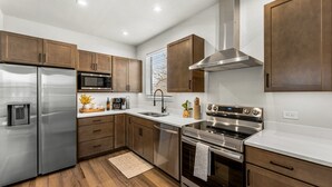 Una cocina moderna con electrodomésticos de acero inoxidable, gabinetes de madera y una encimera blanca.