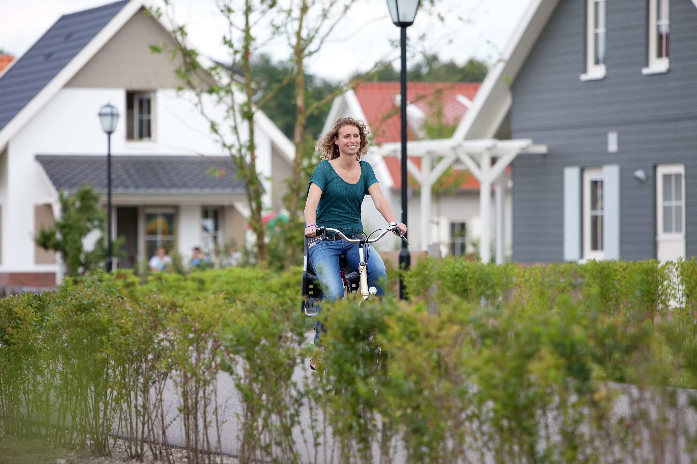 A person riding a bicycle on a path with houses in the background.