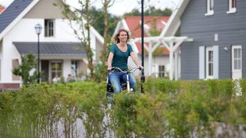 A person riding a bicycle on a path with houses in the background.