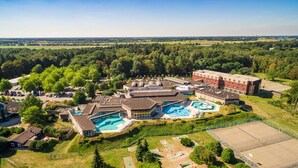 A large hotel with multiple swimming pools, a tennis court, and a parking area surrounded by greenery. - Lodge by the Lake in Arcen's Tranquil Nature (Arcen)