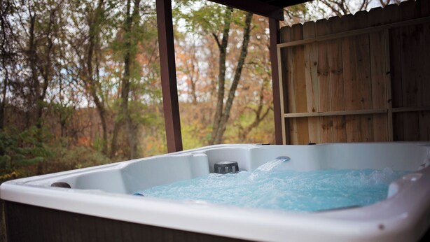 Ein Whirlpool mit einer Holzterrasse und Blick auf Bäume.