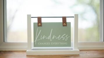 Un cartel enmarcado con la inscripción 'Kindness Changes Everything' colgado en el alféizar de una ventana.