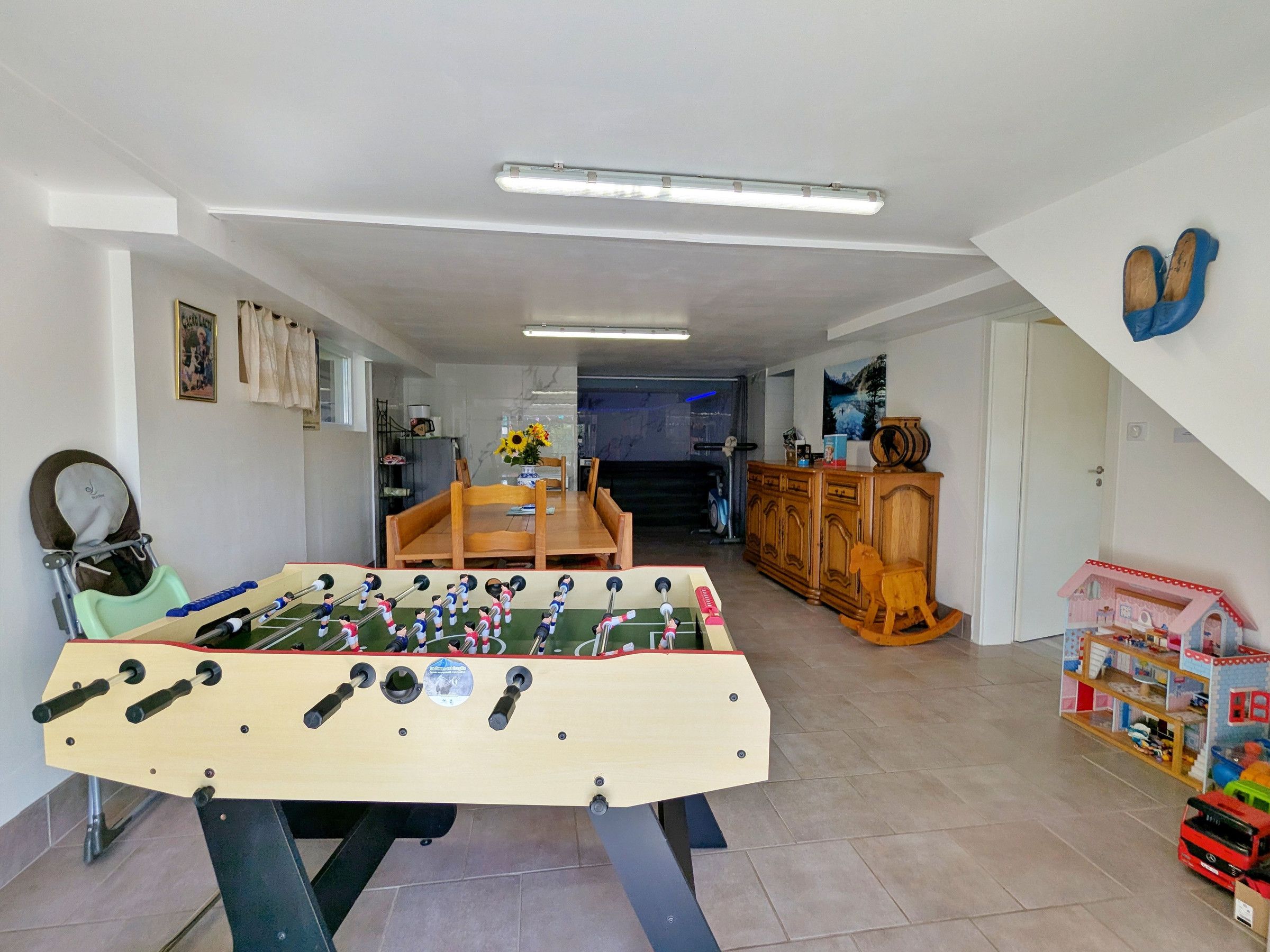 Quarto com mesa de pebolim, mesa de jantar e área de recreação infantil.
