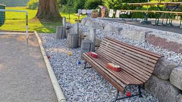 A park bench with a bag and a red object on it, surrounded by gravel and rocks.