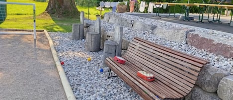 Un banc de parc avec un sac et un objet rouge posés dessus, entouré de gravier et de rochers.
